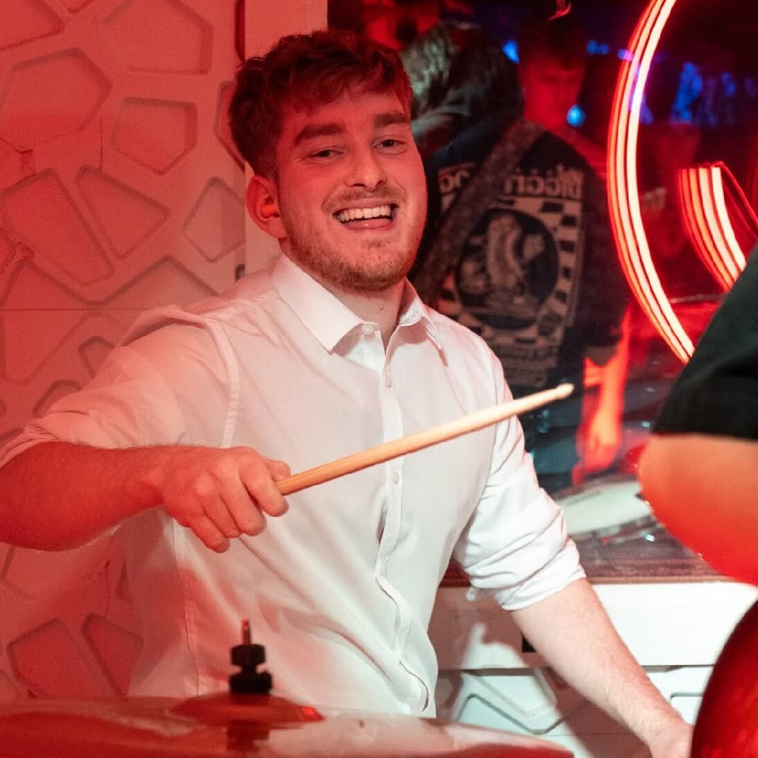 Jensen smiling while playing drums